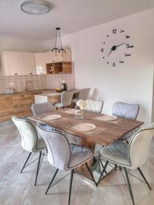 a dining room table with chairs and a clock on the wall at New, modern, luxury apartment Ivan with jacuzzi in Drinovci