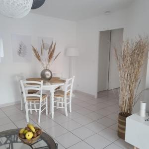 a white dining room with a table and chairs at Appartement 63 m2, tout confort, climatisé. in Saint-Cyprien