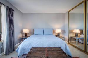 1 dormitorio con 1 cama, 2 lámparas y espejo en Great Vibe House + Hot Tub, Minutes to JTree Park, en Twentynine Palms