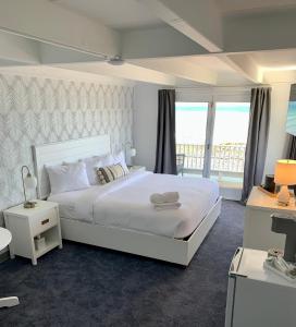 a bedroom with a large white bed and a balcony at Grand View Hotel in York Beach
