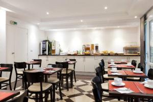 a restaurant with tables and chairs and a kitchen at The Originals City, Hôtel Paris Sud, Orly-Draveil in Draveil
