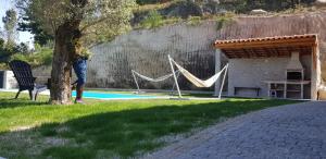 eine Person, die neben einem Baum neben einem Pool steht in der Unterkunft Casa da Batoca - Rossas in Vieira do Minho