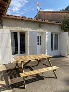 a wooden picnic table in front of a building at Gîte le verger in Soulignonne