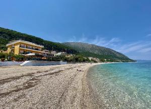 a sandy beach with a building and the ocean at Riviera Hotel in Poros