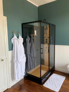 Una ducha de cristal en una habitación con ropa en ganchos en Maison de l'Aumance, en Meaulne