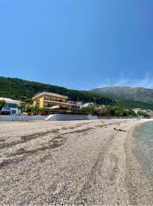 piaszczysta plaża z budynkiem i oceanem w obiekcie Riviera Hotel w mieście Poros