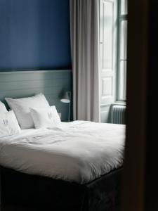 a bed with white sheets and a blue wall and a window at Saint SHERMIN bed breakfast & champagne in Vienna