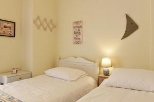 une chambre avec deux lits et une table avec une lampe dans l'établissement Nostos Apartment, à Ermoúpoli