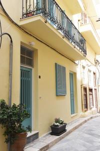 un bâtiment jaune avec un balcon et quelques plantes dans l'établissement Nostos Apartment, à Ermoúpoli