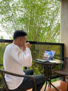 a man sitting at a table with a laptop computer at Red Palm Inn balcony room with Netflix in Baybay