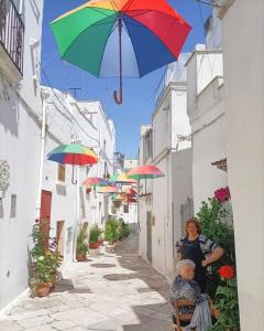 uma mulher e uma criança sentados numa cadeira debaixo de um guarda-chuva em Le luminarie em Mottola