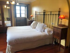 a bedroom with a large bed with white sheets and pillows at Casa Grande de Fuentemayor in Silleda
