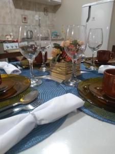 a table with wine glasses and plates and napkins at Casa e Flat Conforto Gramado in Gramado