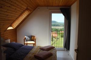 a bedroom with a bed and a large window at Napsugár Vendégház in Badacsonytördemic