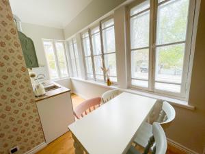 a kitchen with a white table and some windows at Spacious Supeluse Apartment in Pärnu