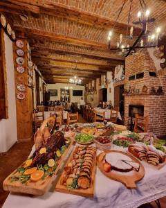 uma mesa com muitos tipos diferentes de alimentos sobre ele em Conacul Sfântul Sava Brancovici em Ineu