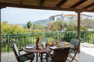 a wooden table and chairs on a balcony with a view at Eleni's House Cozy 2-Bedroom House with Garden in Monemvasia