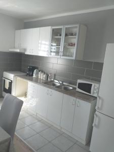 a kitchen with white cabinets and a sink and a refrigerator at Apartment Darinka in Šibenik