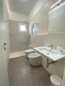 La salle de bains blanche est pourvue d'un lavabo et de toilettes. dans l'établissement Hotel Linda, à Caorle