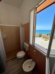 a bathroom with a toilet and a shower and a window at Carrubella Santa Zita in Licata