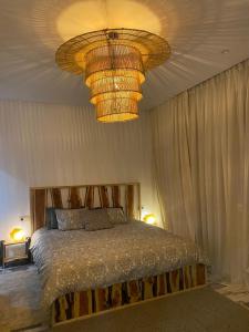 a bedroom with a bed and a large chandelier at Bel Appart Cosy plein coeur de Tanger vue mer in Tangier