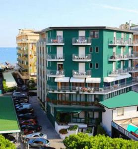 un bâtiment vert avec des voitures garées devant lui dans l'établissement Hotel Colorado, à Lido di Jesolo