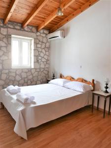 a bedroom with a large bed and a stone wall at Το Λαϊνάκι by Fox Tale Guest House in Fternón