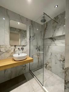 a bathroom with a sink and a glass shower at George Deluxe Apartments in Stalida