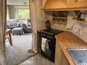 a kitchen with a stove top oven next to a living room at Private Holiday home in calm site in Wootton Bridge