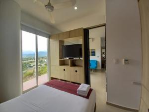 a bedroom with a bed and a tv and a window at Terrazas Tayrona Travelers Apartamentos y Suites in Santa Marta