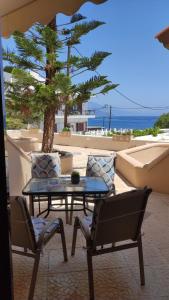 a patio with a table and chairs and a palm tree at Soula Apartments & Studios in Palaiochora