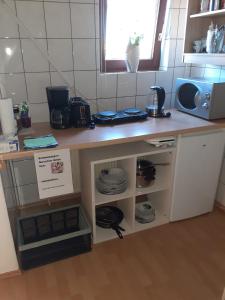 a kitchen with a counter with plates and a microwave at Apartment 3 nähe Barmestedt - Elmshorn in Bokholt-Hanredder
