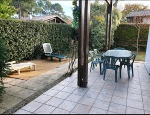 eine Terrasse mit einem Tisch, Stühlen und einer Bank in der Unterkunft Maison idéalement située pour 6 personnes in Soustons