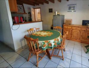 eine Küche mit einem Tisch und Stühlen sowie einem Kühlschrank in der Unterkunft Maison idéalement située pour 6 personnes in Soustons