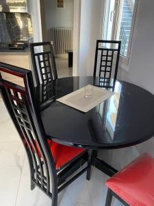 una mesa negra con cuatro sillas y una copa de vino. en luxury apartment 11' from Athens center, en Atenas