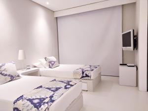 een witte kamer met 2 bedden en een televisie bij Morros 3 Apartamentos de Lujo in Cartagena