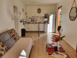 een woonkamer met een bank en een keuken bij Les Ti Kaz a Papé in Deshaies