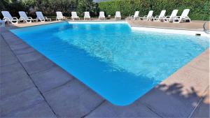 einen Pool mit Stühlen und einem blauen Pool in der Unterkunft L'Atalante, 2 pièces 47m2 rénové résidence piscine in Villeneuve-Loubet