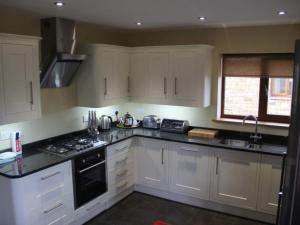 a kitchen with white cabinets and black counter tops at Cherry Lodge in Penrith +8 photos
