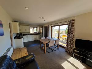 a living room with a table and a kitchen at Cherry Lodge in Penrith