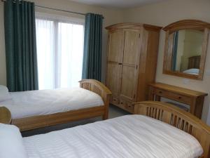 a bedroom with two beds and a dresser and a mirror at Cherry Lodge in Penrith