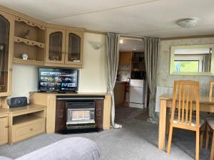 a room with a kitchen with a table and a tv at Private Holiday home in calm site in Wootton Bridge