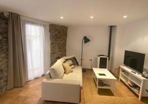 uma sala de estar com um sofá branco e uma televisão em Apartamento con encanto en el Pirineo em La Pobla de Lillet