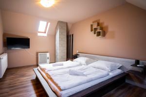 1 cama blanca grande en una habitación con TV en Lator-Boross Vendégház en Villány