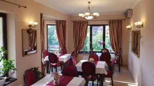 un restaurante con mesas, sillas y ventanas en Pensiunea Toscana, en Brasov