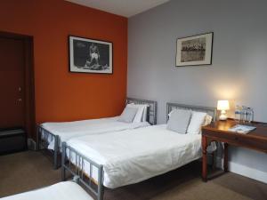 2 camas en una habitación de hotel con mesa y escritorio en The Orchard Hotel en Falkirk