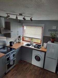 a kitchen with a sink and a washing machine at Ella's Hoose in Wick
