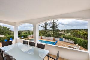 een eetkamer met een tafel en uitzicht op een zwembad bij CoolHouses Algarve Lagos, 4 bed single-story House, pool and amazing panoramic views, Casa Fernanda in Lagos