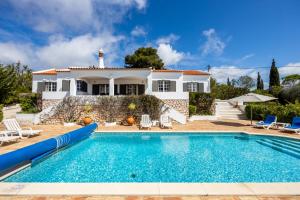 a villa with a swimming pool in front of a house at CoolHouses Algarve Lagos, 4 bed single-story House, pool and amazing panoramic views, Casa Fernanda in Lagos