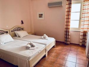 two beds in a small room with a window at A Hotel in Spetses